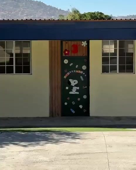 Colegio Encinos building with a decorated classroom door and the Tecate hills behind