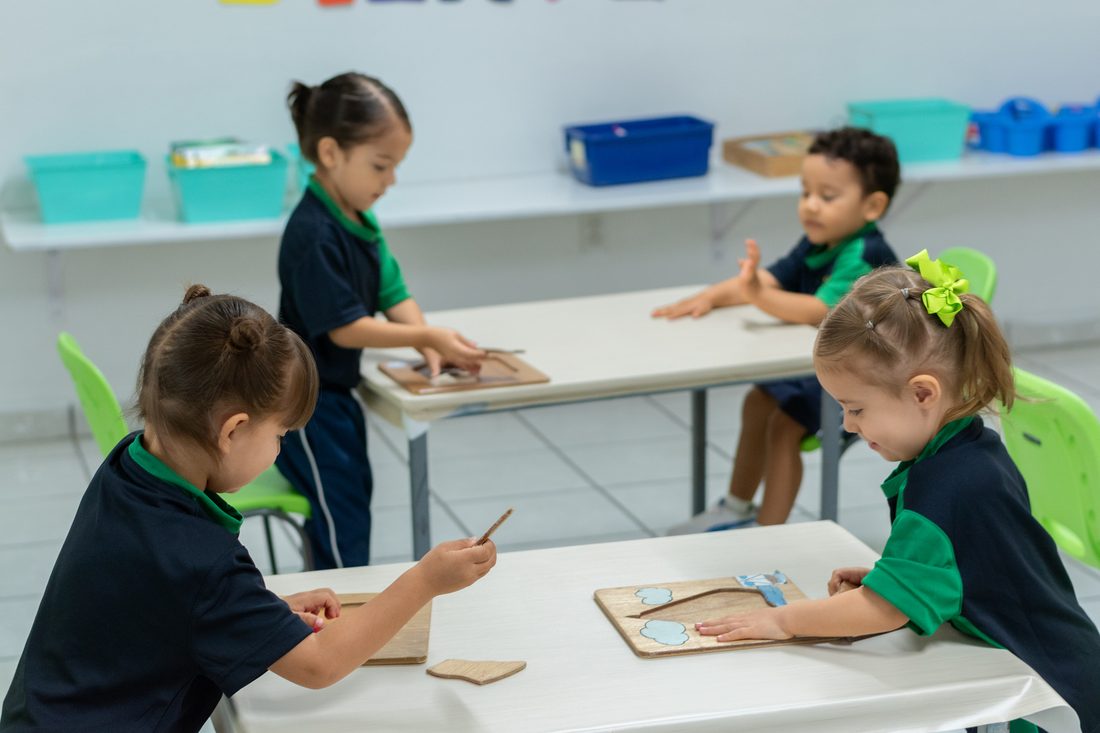 Niñas y niños de preescolar trabajando con material didáctico en las mesas del salón