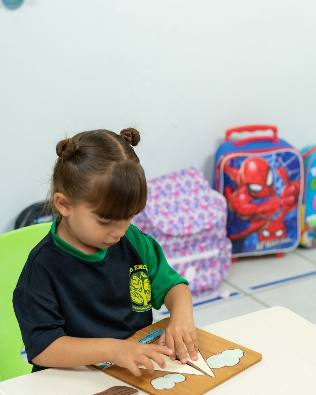 Preschool girl fitting pieces into a wooden puzzle at her table