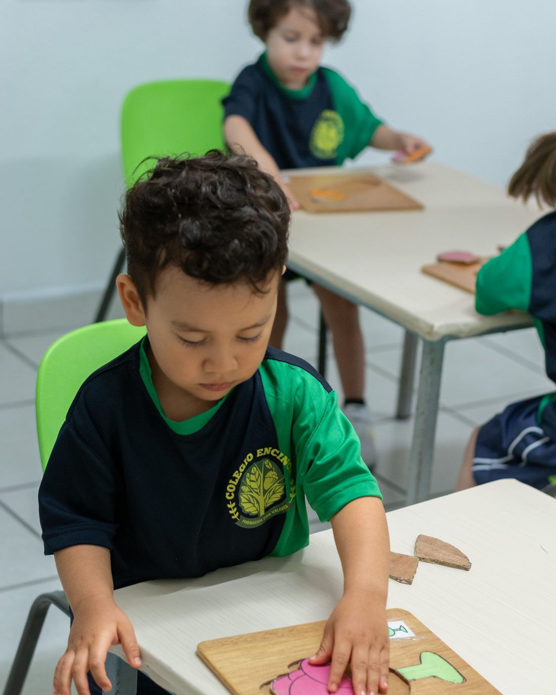 Preschool boy placing a pink piece into his wooden shape board