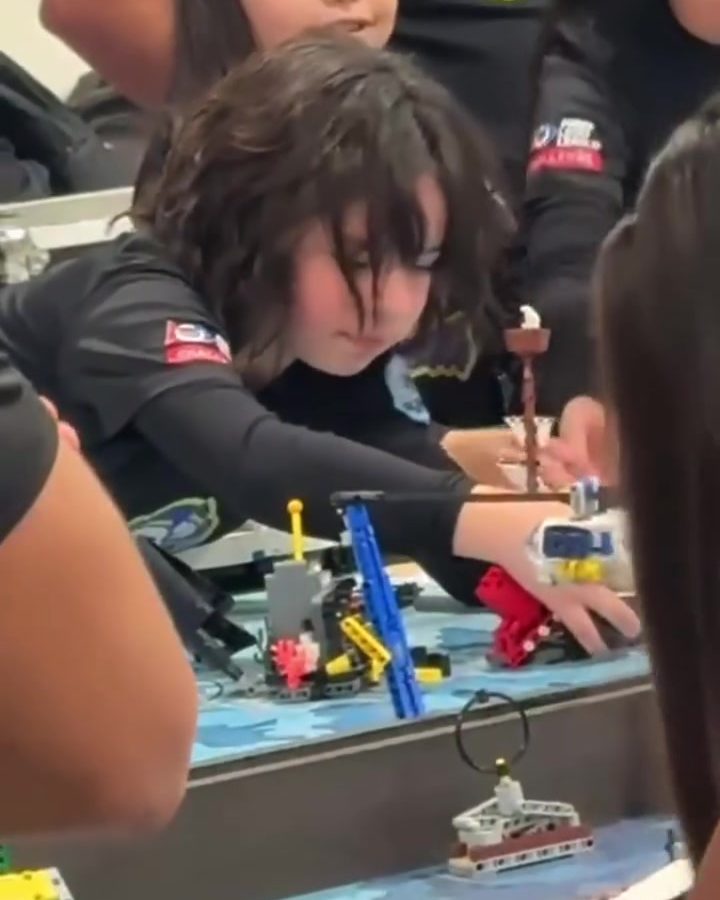 Elementary student adjusting the parts of her LEGO robot on the competition board